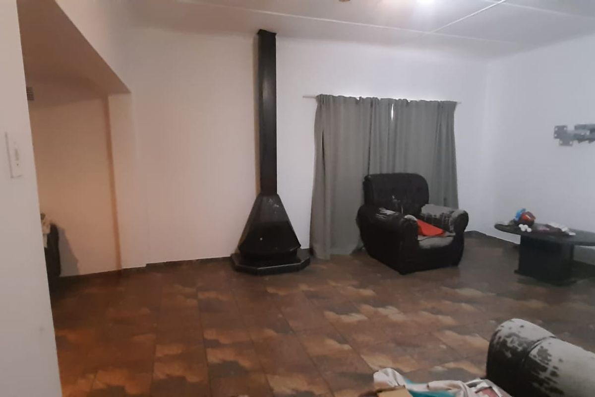 A living room featuring a freestanding fireplace and tiled flooring, offering a blank canvas for renovation and interior design updates.