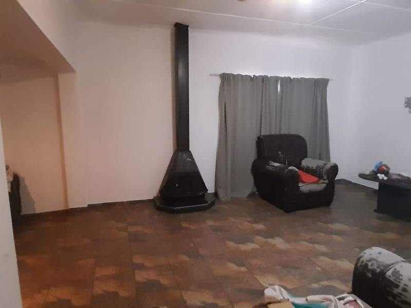 A living room featuring a freestanding fireplace and tiled flooring, offering a blank canvas for renovation and interior design updates.