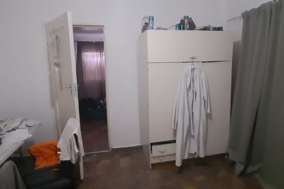 A bedroom featuring parquet flooring and a built-in wardrobe, with an adjacent doorway leading to another room.