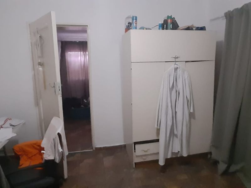 A bedroom featuring parquet flooring and a built-in wardrobe, with an adjacent doorway leading to another room.