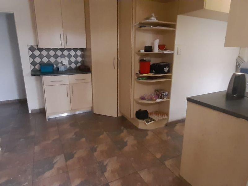 A dated kitchen featuring laminate cabinetry, dark countertops, and tiled flooring, offering potential for a modern renovation.