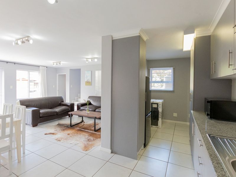 Spacious open-plan living area featuring a modern kitchen with granite countertops, tiled flooring, and seamless flow to the lounge and dining space.