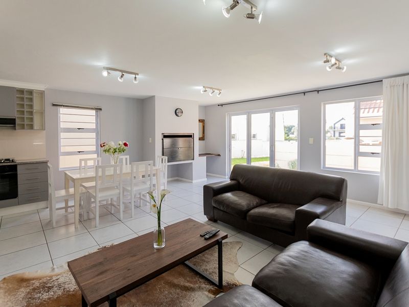 Spacious open-plan living area featuring a modern kitchen with built-in appliances, a fireplace, and direct access to the outdoor space through sliding glass doors.