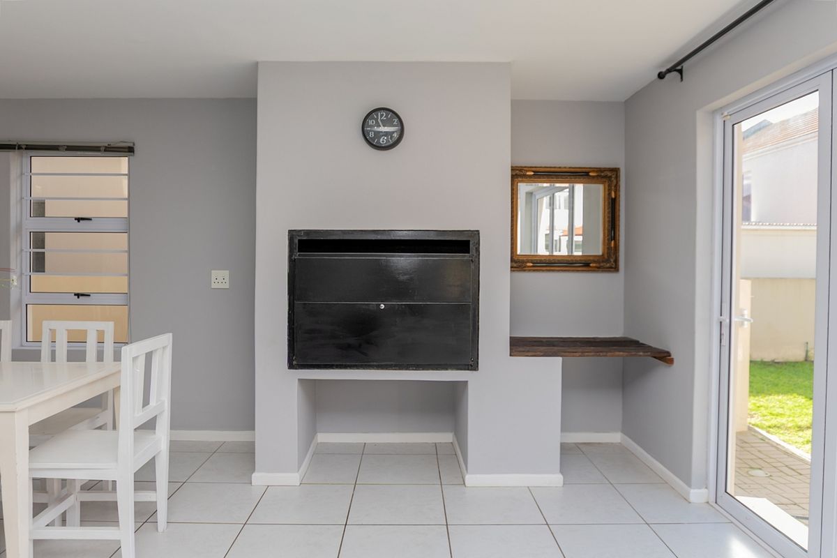 Living area featuring a built-in fireplace, neutral tiled flooring, and direct access to the garden through a sliding glass door.