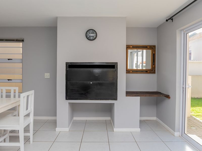 Living area featuring a built-in fireplace, neutral tiled flooring, and direct access to the garden through a sliding glass door.