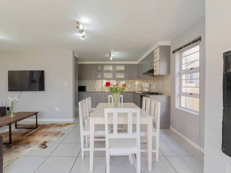 Open-plan living and dining area featuring a modern kitchen with built-in cabinetry, gas hob, and tiled flooring throughout.