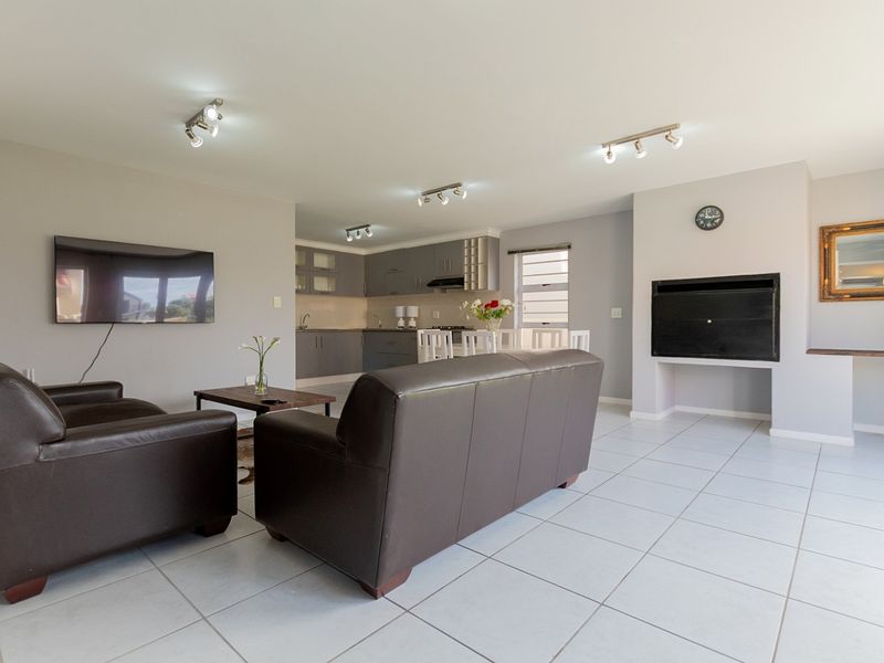 Spacious open-plan living area featuring a modern kitchen with built-in cabinetry, tiled flooring, and a built-in fireplace.