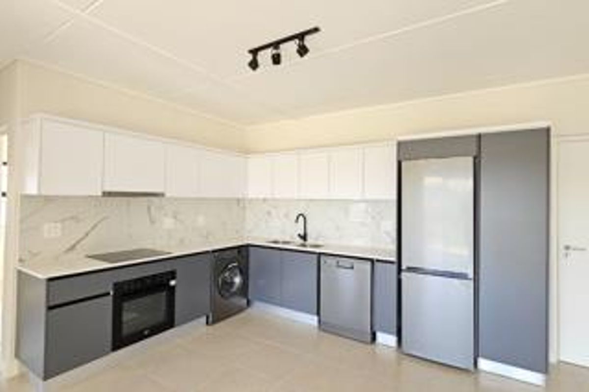 Modern kitchen featuring sleek two-tone cabinetry, marble-look splashback, integrated oven, electric hob, and high-quality finishes in a clean, contemporary layout.