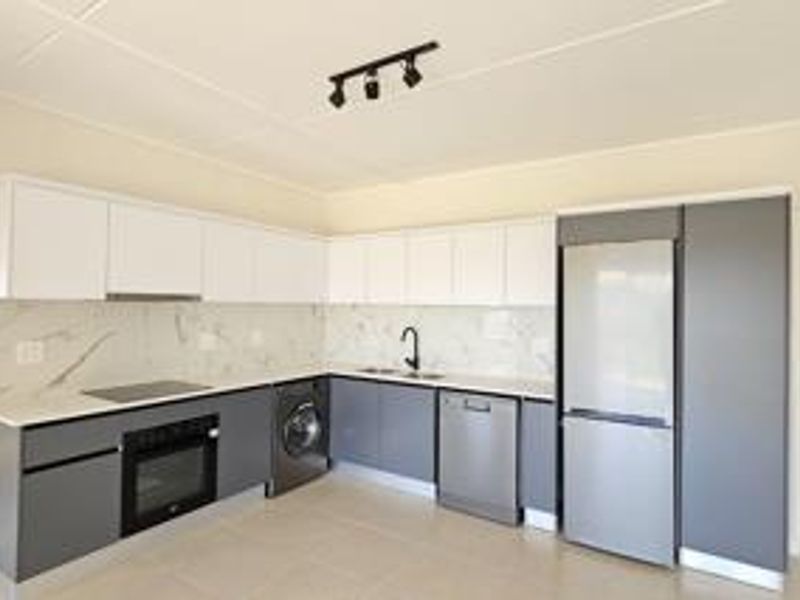 Modern kitchen featuring sleek two-tone cabinetry, marble-look splashback, integrated oven, electric hob, and high-quality finishes in a clean, contemporary layout.
