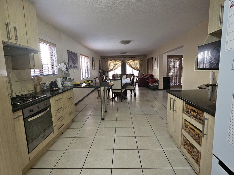 Open-plan kitchen and dining area featuring light wood cabinetry, granite countertops, and neutral ceramic floor tiles throughout the living space.