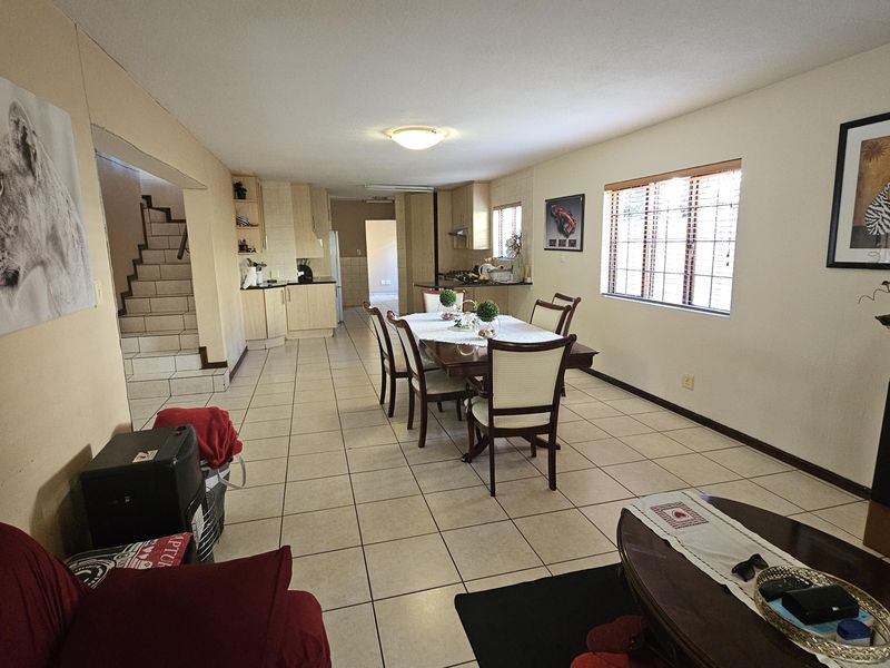 Open-plan living and dining area featuring tiled flooring, a staircase, and an integrated kitchen with built-in cabinetry.