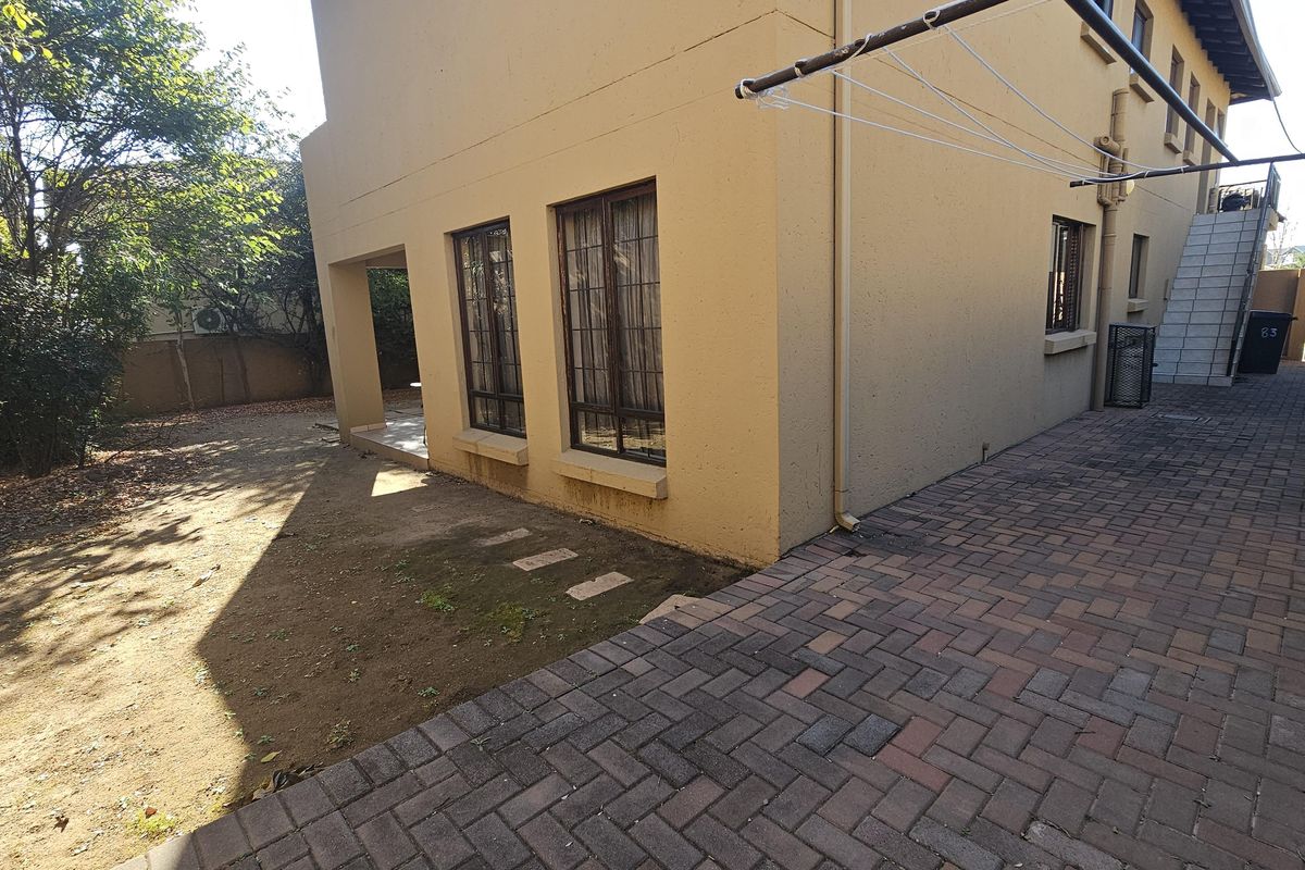 Rear exterior view of the property featuring a paved driveway, plastered facade, and an external staircase leading to the upper level.