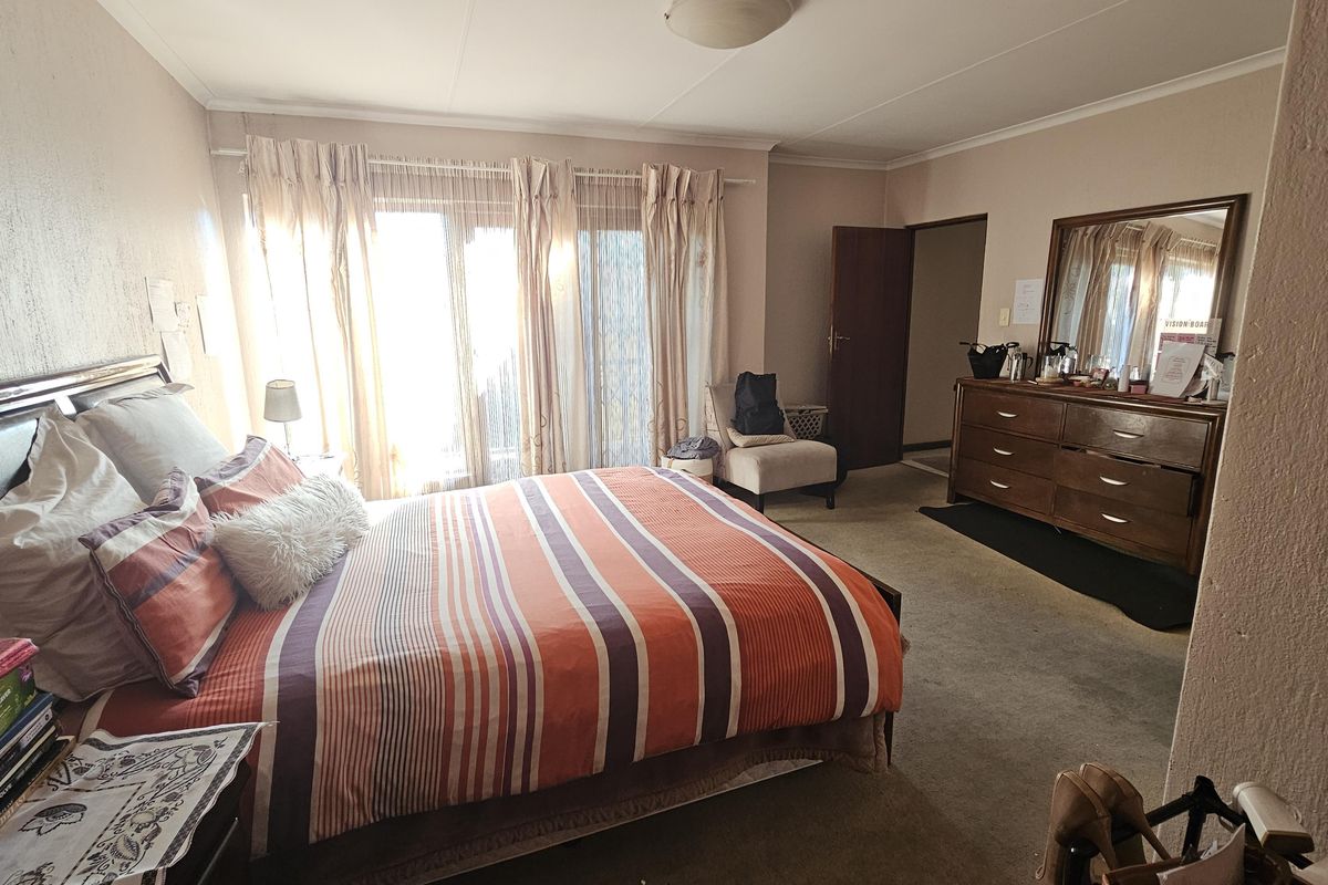 Spacious bedroom featuring carpeted flooring, neutral wall tones, and a sliding glass door providing natural light access.
