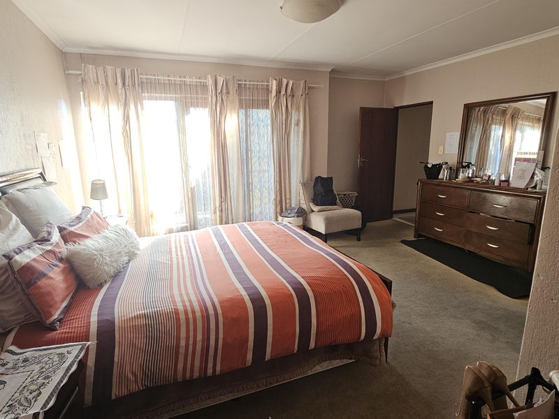 Spacious bedroom featuring carpeted flooring, neutral wall tones, and a sliding glass door providing natural light access.