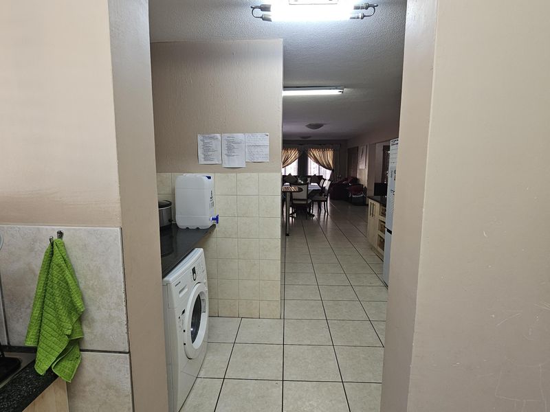 Open plan living area featuring tiled flooring and a dedicated laundry nook with built-in plumbing connections.