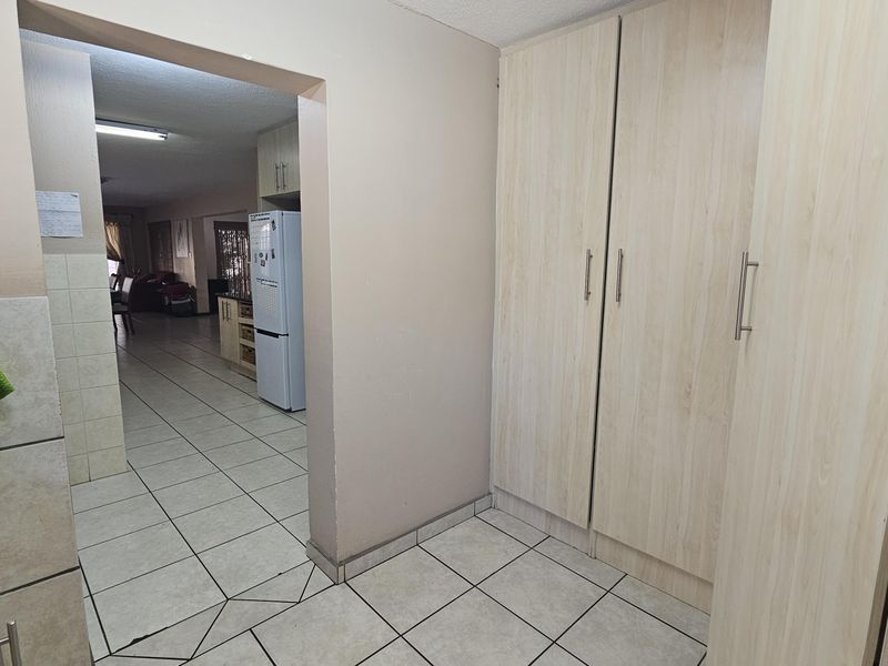 A functional kitchen area featuring light wood-finish built-in cabinetry and tiled flooring, providing a clean and practical layout with direct access to the living space.