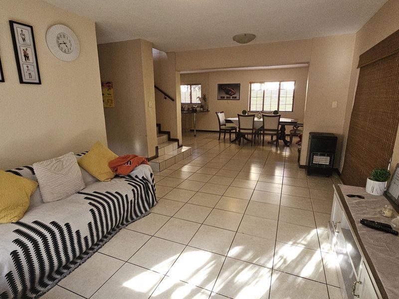 Spacious open-plan living and dining area featuring neutral tiled flooring and a staircase leading to the upper level.