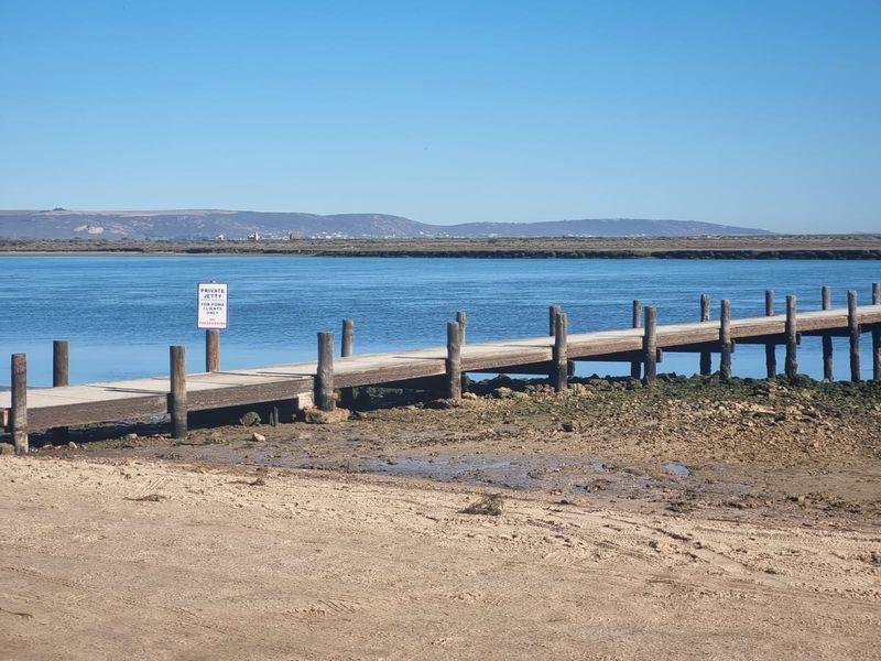 A scenic view of a private wooden jetty extending into the water, highlighting the property's waterfront access and coastal location.