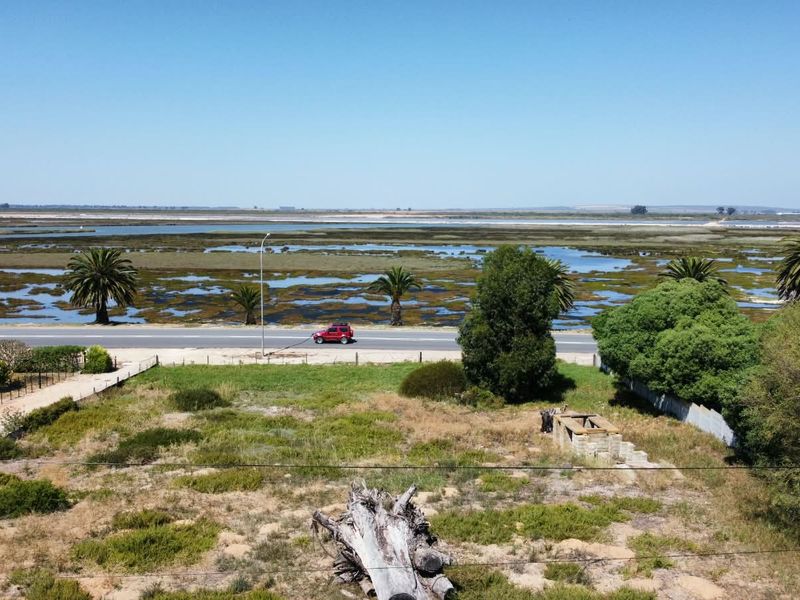 Aerial view of the property grounds featuring a stone masonry structure, natural vegetation, and surrounding landscape with road and wetland access.