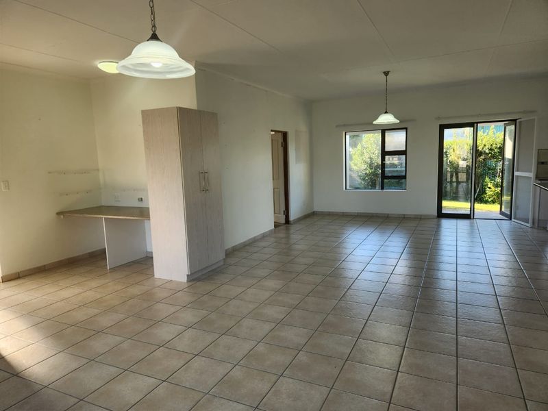 Spacious open-plan living area featuring neutral tiled flooring, built-in cabinetry, and direct access to the outdoor space through sliding glass doors.