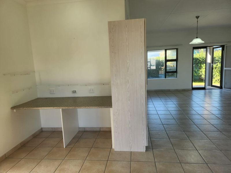 An open-plan living area featuring tiled flooring, a basic kitchen prep counter, and direct access to the outdoor space through sliding glass doors.