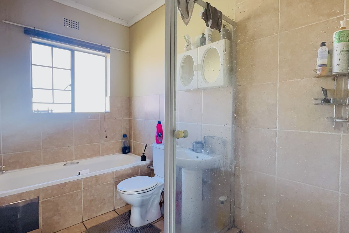 A functional bathroom featuring a bathtub, pedestal basin, toilet, and a separate shower enclosure with tiled finishes throughout.