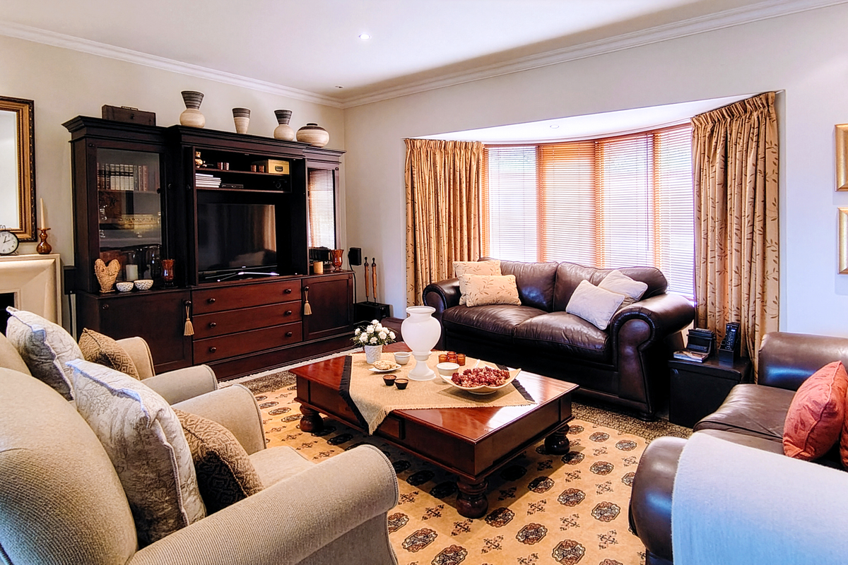 A well-maintained living room featuring a large bay window, coving, and a classic fireplace mantel, creating a comfortable and traditional atmosphere.