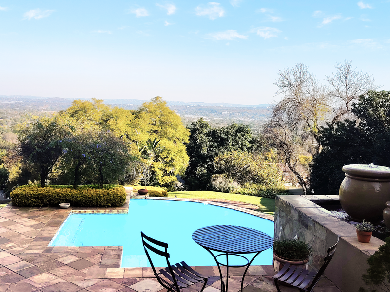 A scenic pool area featuring a stone-paved patio, a decorative water feature, and expansive views of the surrounding landscape.