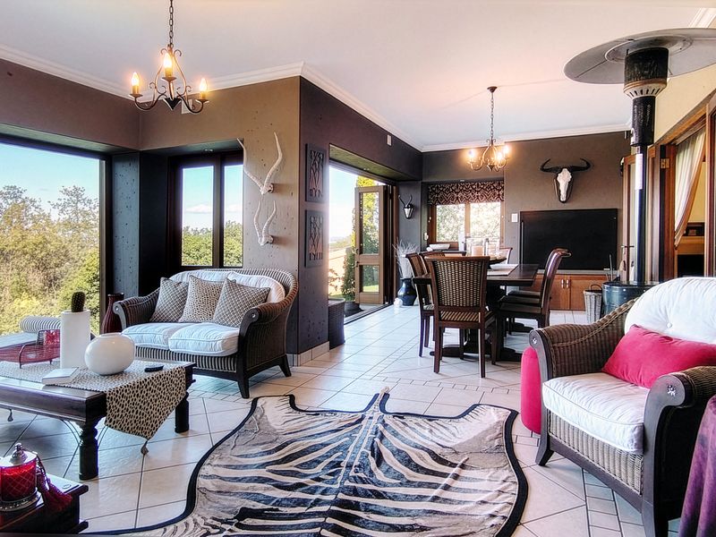 Spacious open-plan living and dining area featuring tiled floors, large sliding doors with scenic views, and elegant wrought iron lighting fixtures.