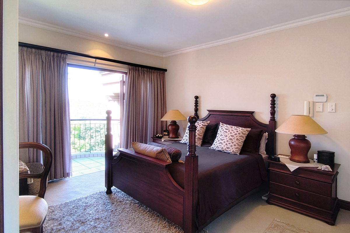 A well-maintained bedroom featuring neutral walls, cove molding, and a sliding glass door providing direct access to a private balcony.