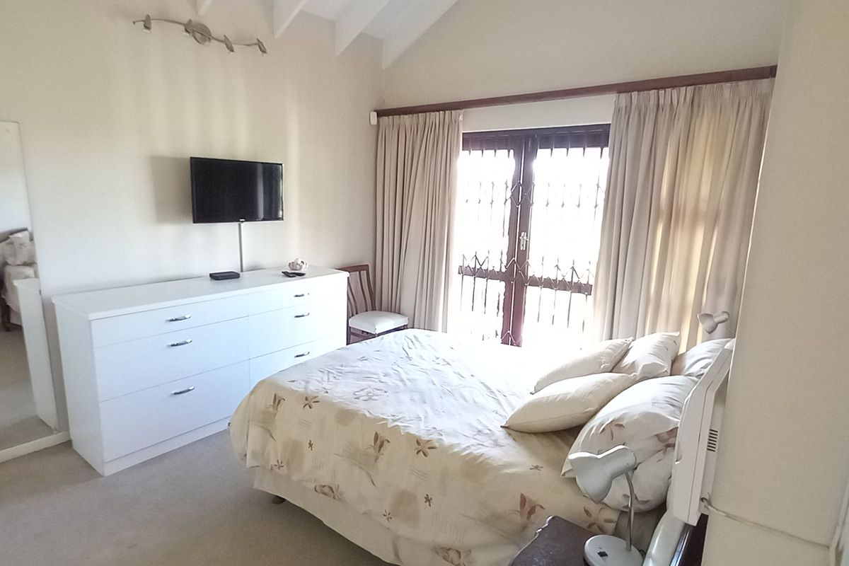 A bedroom featuring a vaulted ceiling, carpeted flooring, and a security gate leading to an outdoor area.