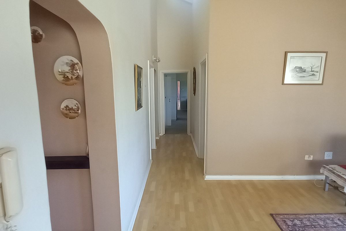 A living area featuring laminate flooring, an arched entryway, and an integrated intercom system, leading into a central hallway.
