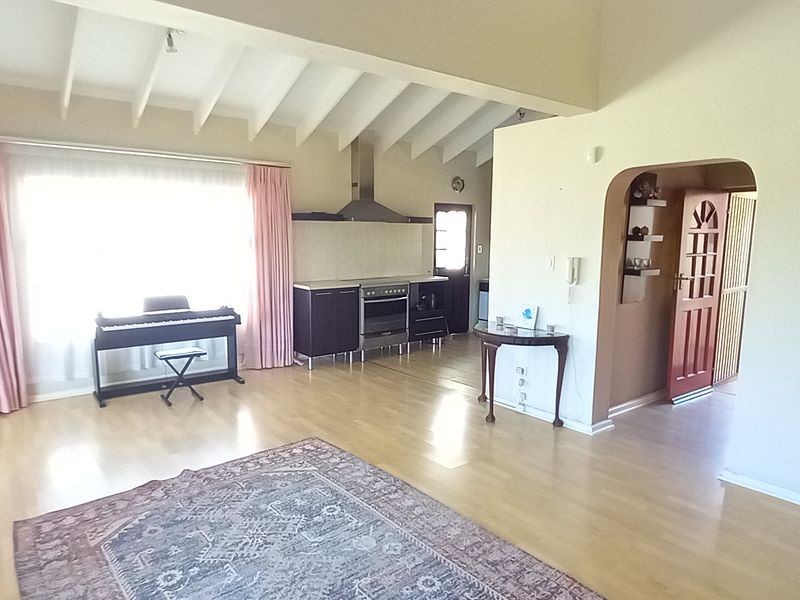 Spacious open-plan living area featuring exposed beam ceilings, laminate flooring, and an integrated kitchen zone with a stainless steel extractor fan.