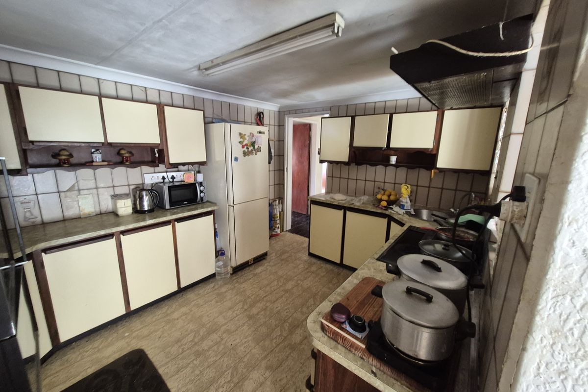 A dated kitchen featuring laminate cabinetry, tiled backsplash, and functional layout, offering significant potential for modernization and renovation.