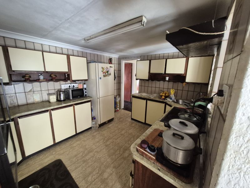 A dated kitchen featuring laminate cabinetry, tiled backsplash, and functional layout, offering significant potential for modernization and renovation.
