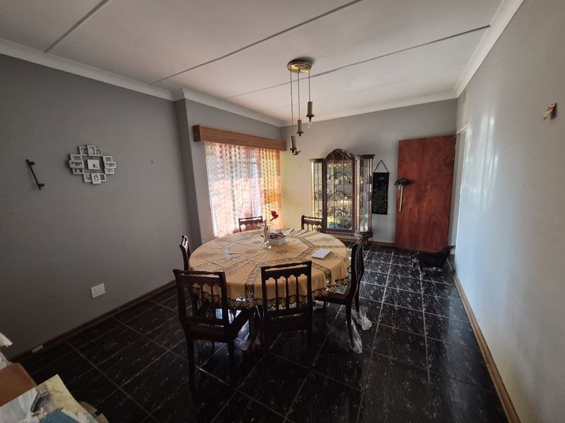 A dining room featuring dark tiled flooring, coved ceilings, and a central pendant light fixture.