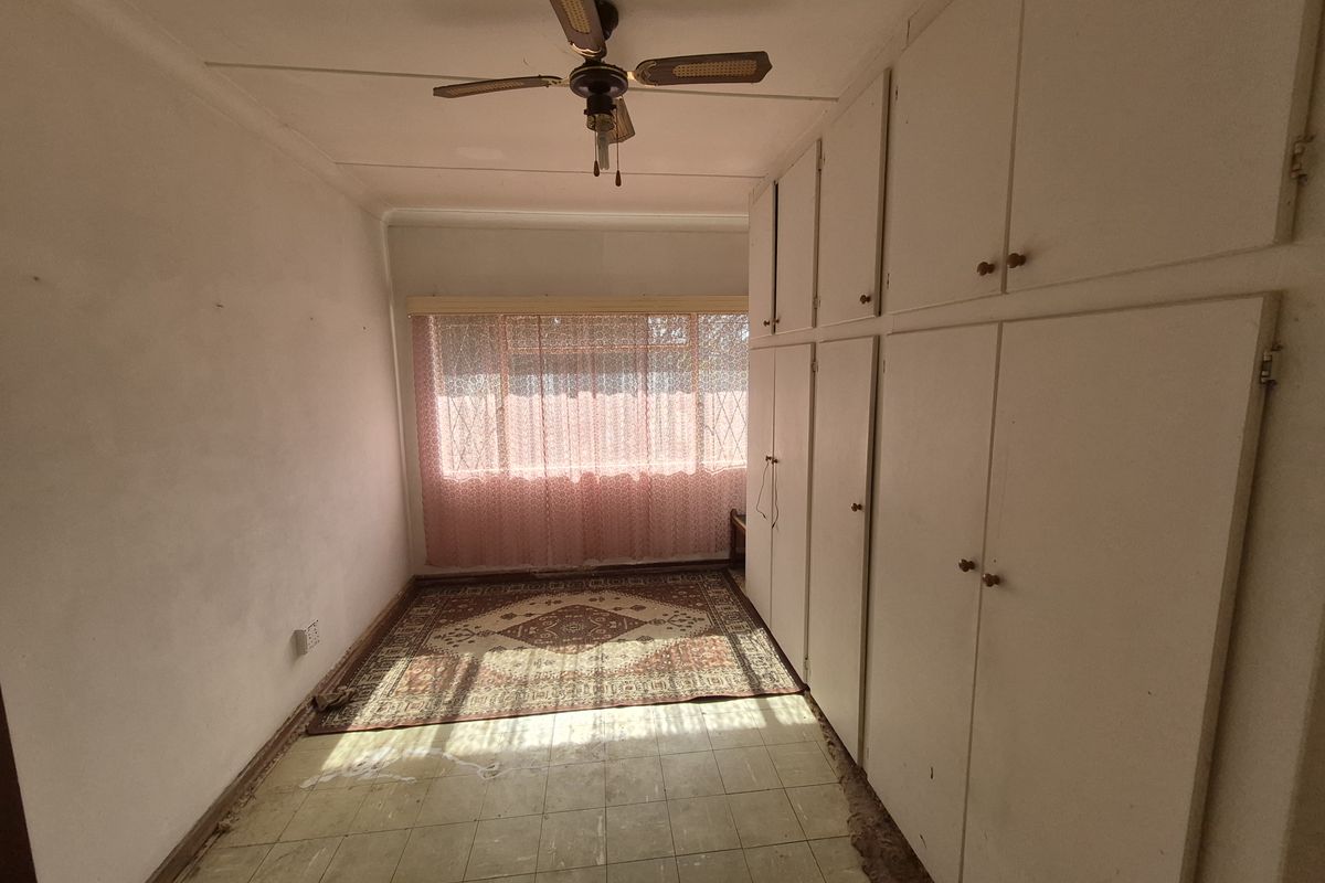 A bedroom featuring built-in cupboards, a ceiling fan, and vinyl flooring. The space is vacant and ready for renovation or restyling.