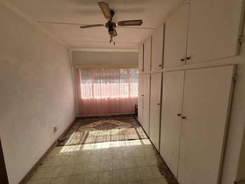A bedroom featuring built-in cupboards, a ceiling fan, and vinyl flooring. The space is vacant and ready for renovation or restyling.