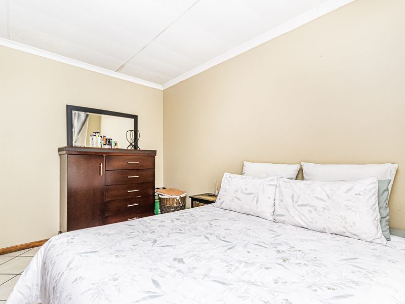 A standard bedroom featuring tiled flooring and a coved ceiling, providing a functional and neutral space.