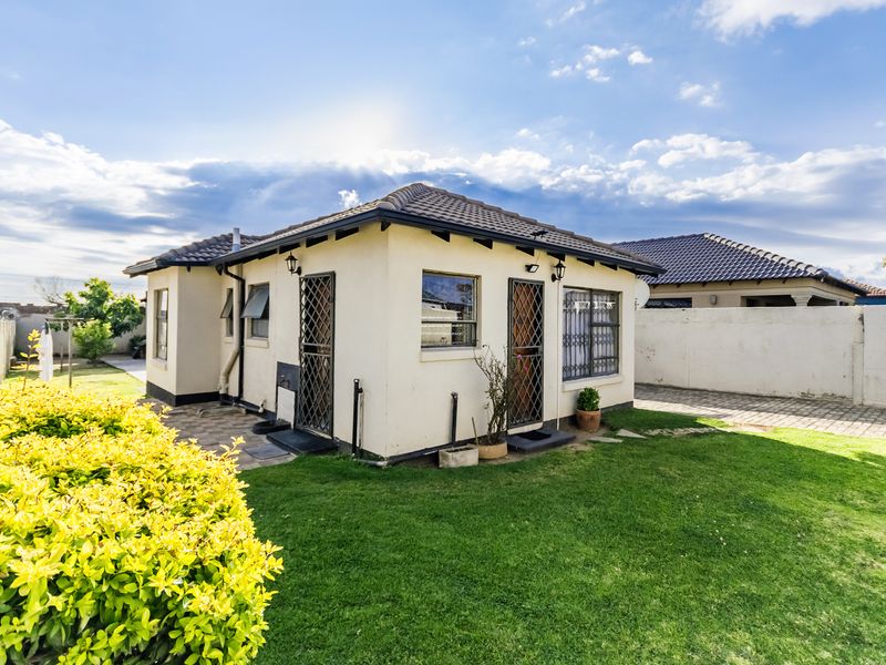 Rear view of the house featuring a tiled roof, security gates, and a well-maintained garden area with paved pathways.