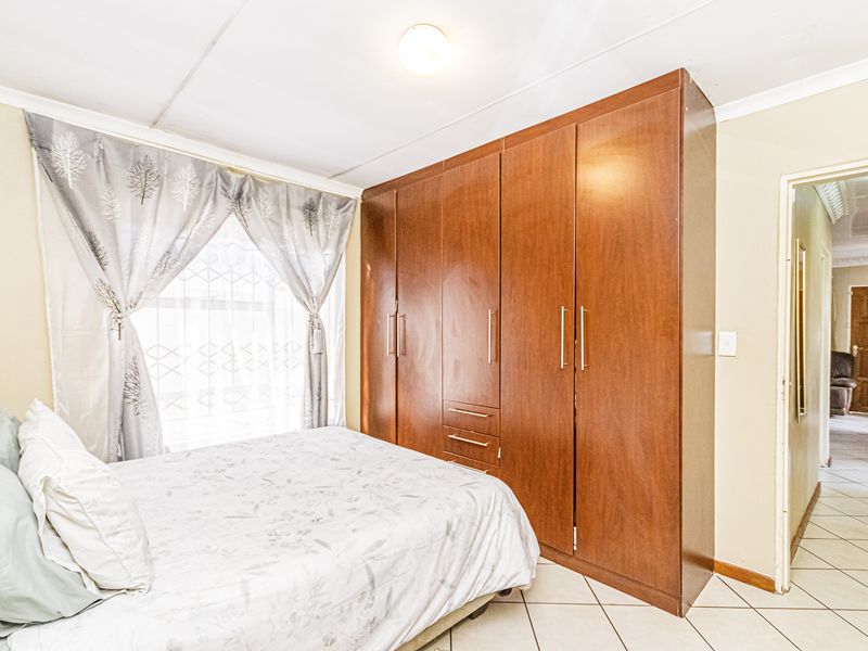 A bedroom featuring built-in wooden wardrobes, tiled flooring, and neutral wall finishes, providing functional storage and a clean layout.