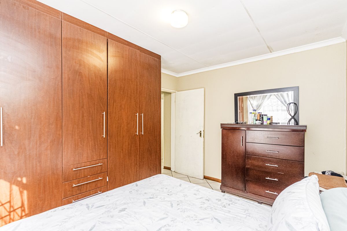 A bedroom featuring built-in wooden cupboards and tiled flooring, offering functional storage space.