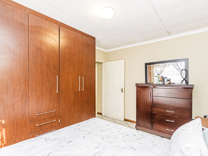 A bedroom featuring built-in wooden cupboards and tiled flooring, offering functional storage space.