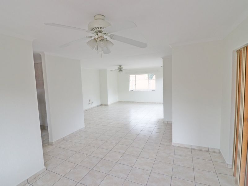 Spacious open-plan living area featuring neutral tiled flooring, ceiling fans, and natural light, providing a versatile blank canvas for interior design.
