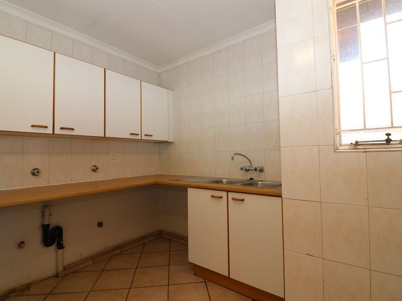 A functional scullery area featuring built-in cabinetry, a double sink, and tiled finishes, offering a practical space for laundry or additional kitchen preparation.