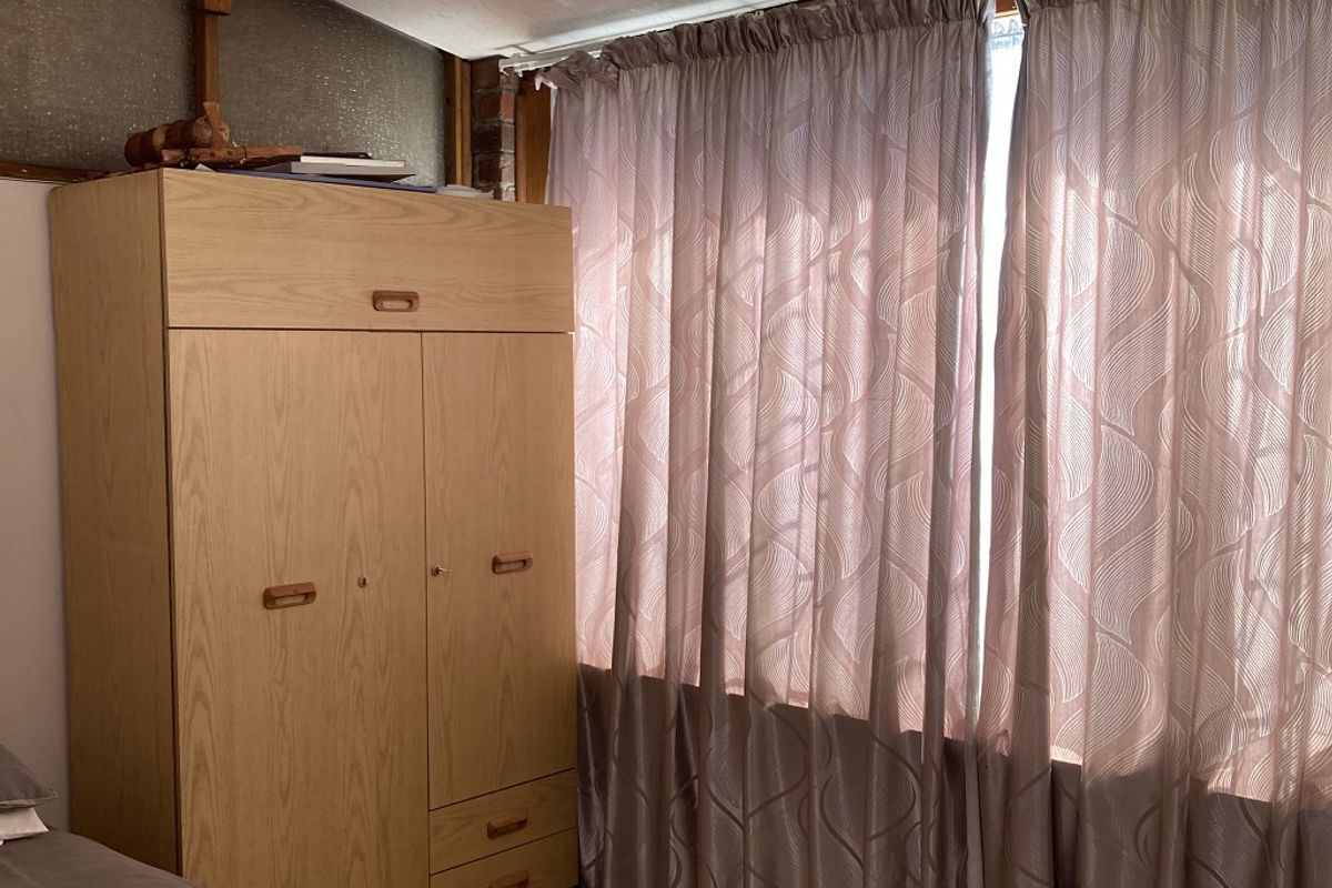 A bedroom featuring carpet flooring and a drop ceiling, currently showing signs of wear and dated finishes.