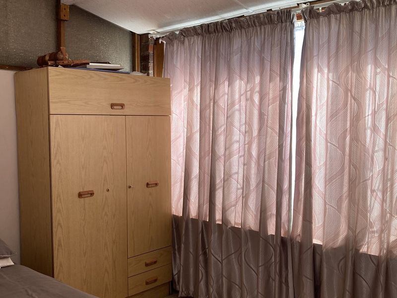 A bedroom featuring carpet flooring and a drop ceiling, currently showing signs of wear and dated finishes.