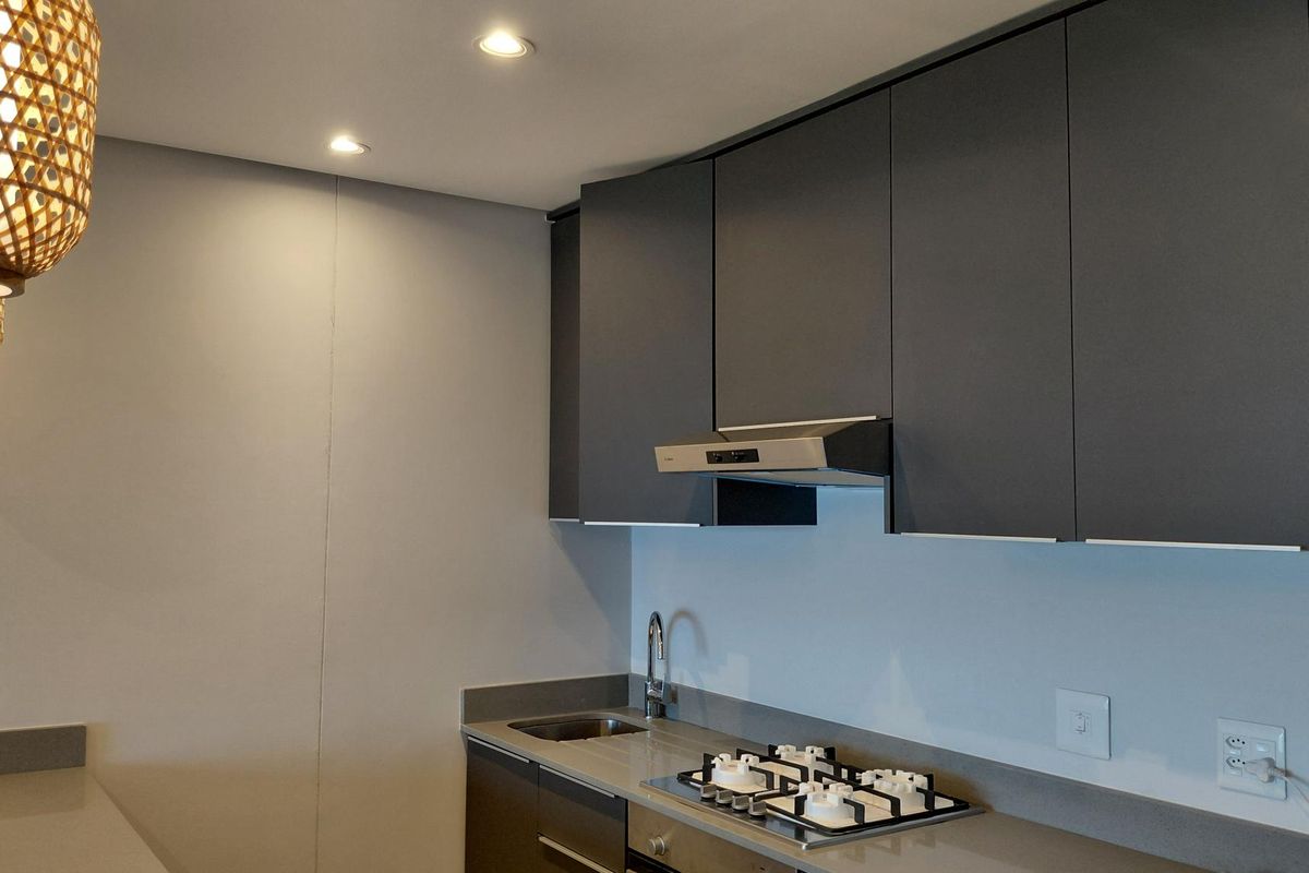Modern kitchen featuring dark matte cabinetry, stone countertops, integrated gas hob, extractor fan, and stainless steel sink with recessed lighting.