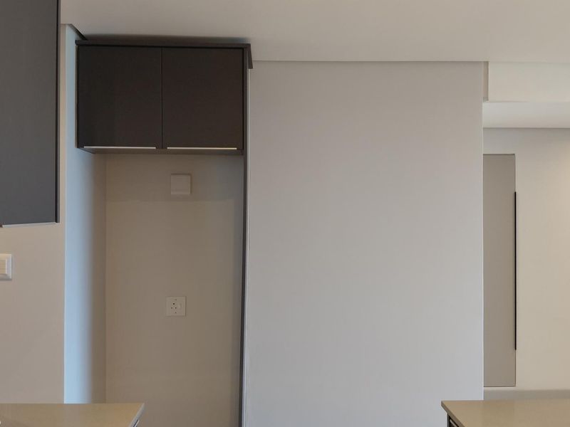 A modern kitchen area featuring built-in cabinetry, stone countertops, and an integrated extractor fan, presented in a clean, minimalist style.