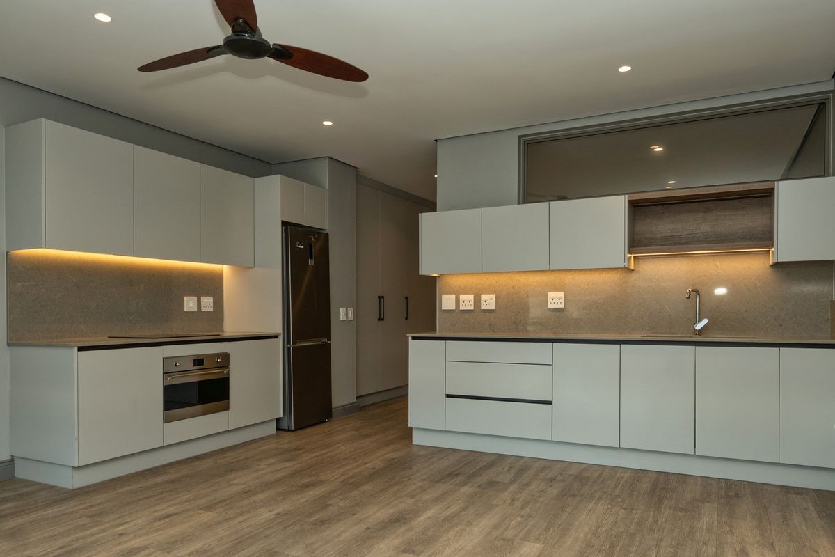 Modern, well-appointed kitchen featuring sleek cabinetry, stone countertops, integrated appliances, and warm under-cabinet lighting, set against high-quality laminate flooring.